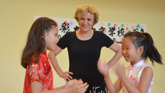 Oberbürgermeisterin Charlotte Britz schaut zwei Mädchen bei einem chinesischen Klatschspiel zu